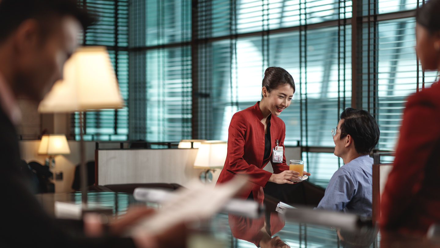 Customer service officer serving drinks to passenger at lounge