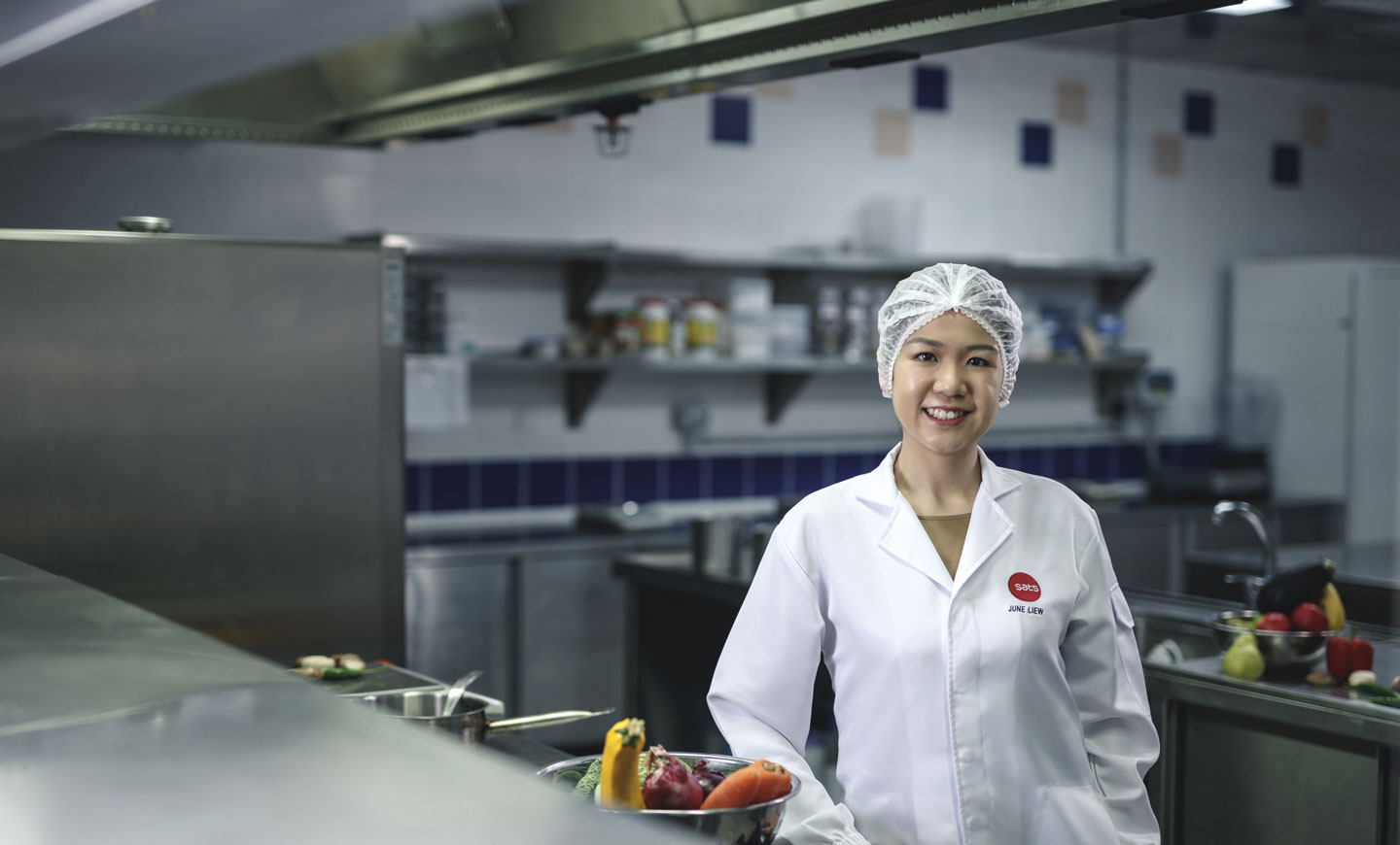 Lady in SATS kitchen with fresh ingredients